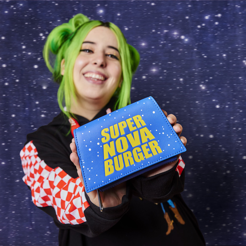 Woman wearing the Pizza Planet hoodie holding out the Super Nova Burger Wallet toward camera
